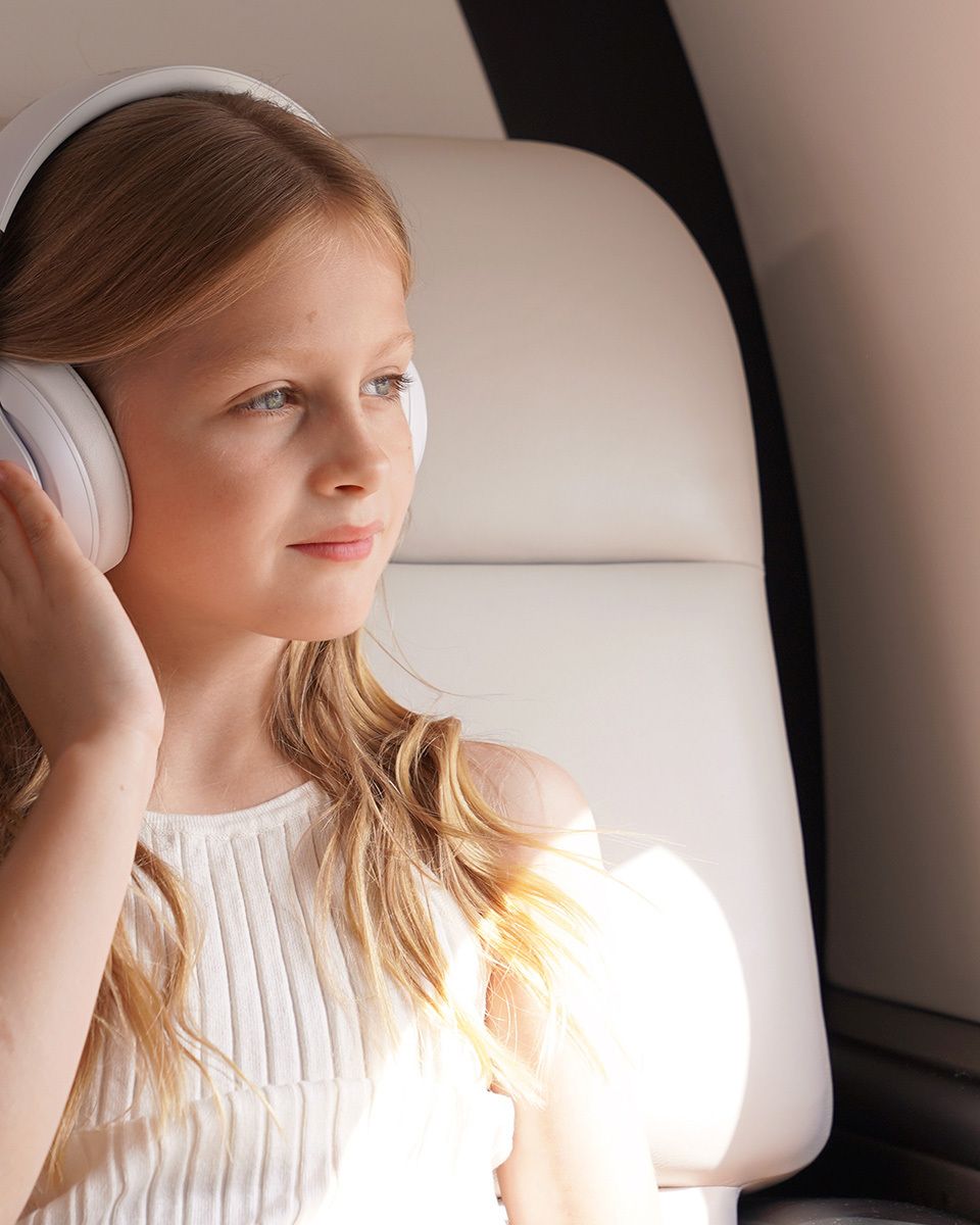 a child wearing headphones looking out a plane window